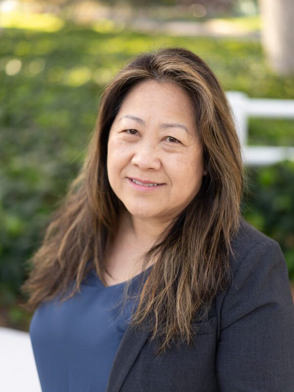 Outdoor photo of asian woman smiling with blurry grass in background